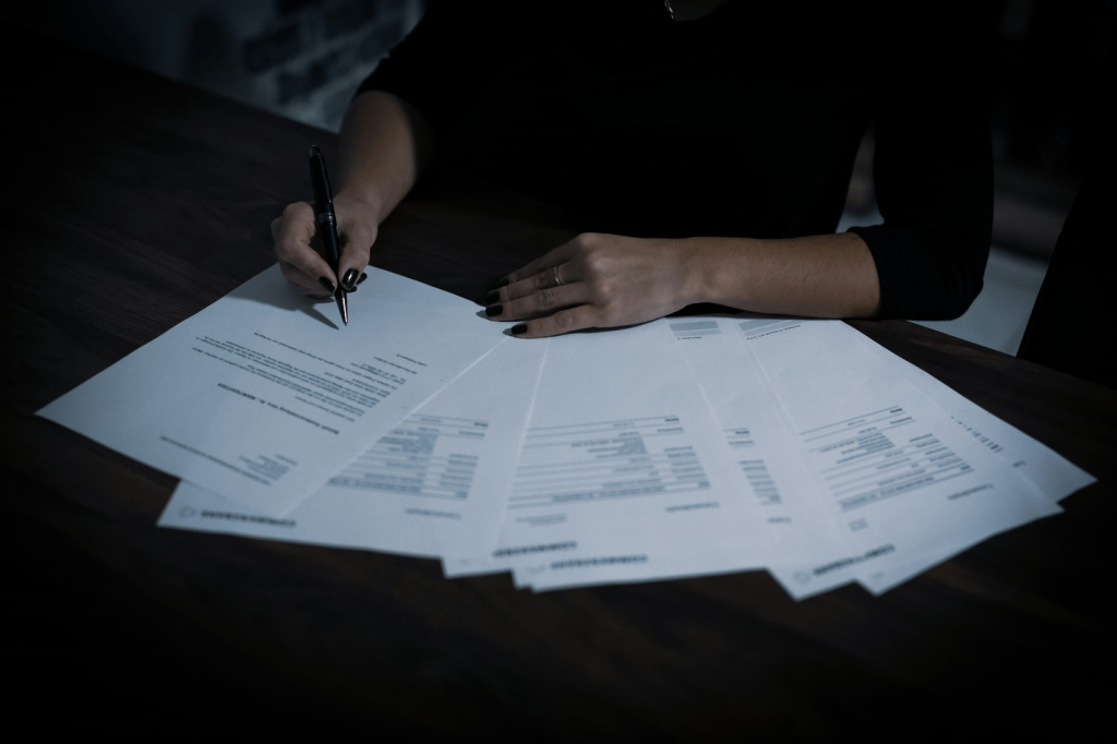 an individual writing on a few documents