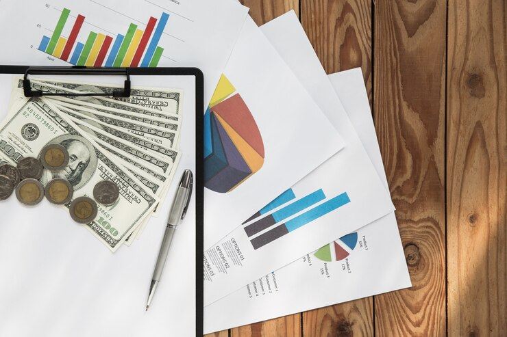 financial charts and money on a wooden background.