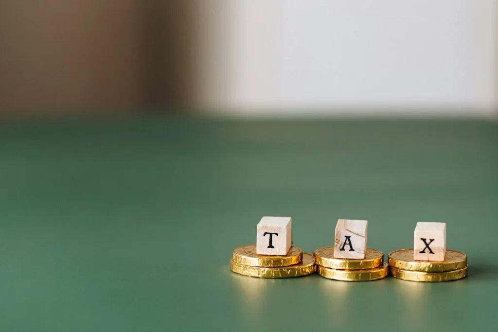 Blocks spelling out TAX placed above a stack of coins