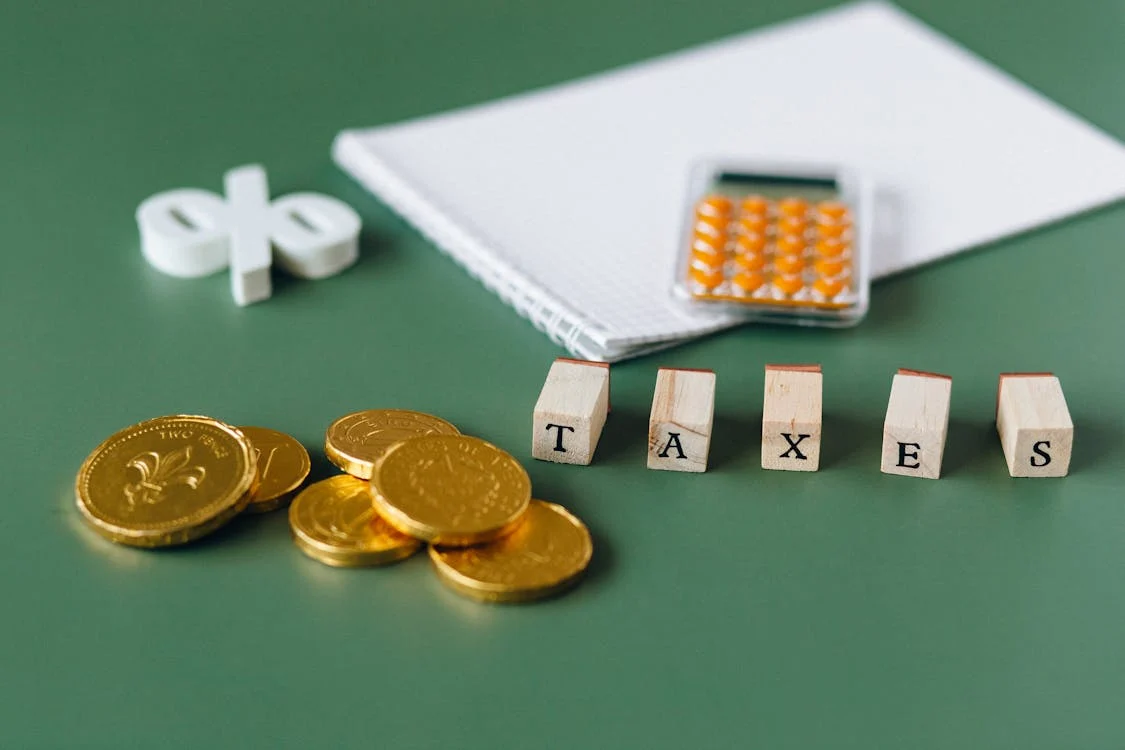 Cubes spelling out TAXES placed next to coins